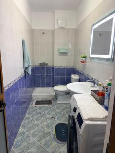 a blue and white bathroom with a toilet and a sink at ASA Apartament in Tirana
