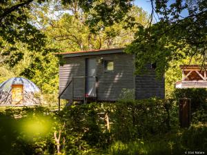 a small black house with a window and trees at Roulotte - Etat Nature in Magnières
