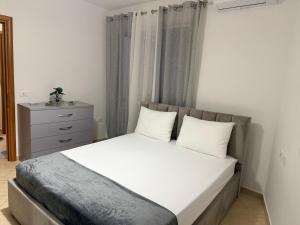 a bed with white sheets and pillows in a bedroom at ASA Apartament in Tirana