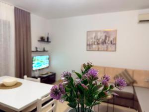 a vase with purple flowers on a table in a living room at ASA Apartament in Tirana