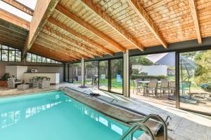 an outdoor swimming pool with a wooden pergola and a house at L'atypique - Piscine intérieure - Wifi in Challans