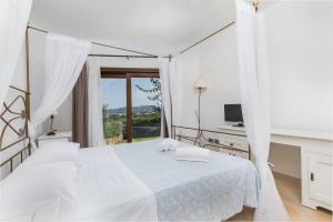 a white bedroom with a bed and a desk and a window at Villa Lu Nibaru 2 in Cannigione