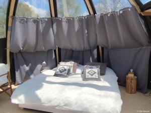 a bed in a tent with pillows on it at Bulle nuage - Etat Nature in Magnières
