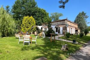 a yard with chairs and a table and a building at Bulle nuage - Etat Nature in Magnières