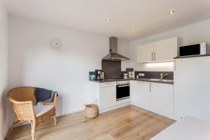 a kitchen with white cabinets and a chair at Ferienwohnung Grübel in Kirchhundem