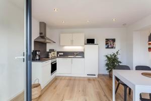 a kitchen with white cabinets and a wooden floor at Ferienwohnung Grübel in Kirchhundem +15 photos