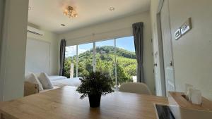 a living room with a table and a large window at Greenery Hill in Ban Nok