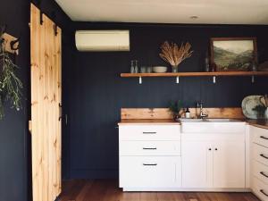 a kitchen with white cabinets and a blue wall at The Milkmans Shack in Dunorlan