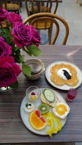 two plates of eggs and fruit on a table with roses at Donners Hotell in Visby