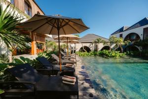 a group of chairs and an umbrella next to a swimming pool at Casa Nova Villa Uluwatu in Uluwatu
