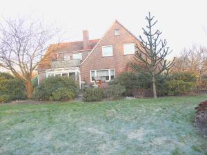 a large brick house with a yard with a tree at Gästehaus an der Wieke in Berumerfehn