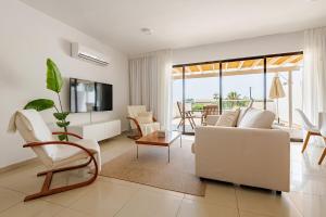 a living room with a white couch and chairs at Oroklini Hills Modern Sea View Apartments in Oroklini