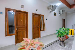 a hallway with wooden doors and a potted plant at RedDoorz at Syariah House Purwokerto in Purwokerto