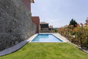 a swimming pool in a yard next to a stone wall at Casas do Bacelar by Liiiving in Quinchães