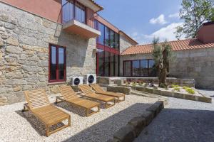 a group of chairs sitting in front of a building at Casas do Bacelar by Liiiving in Quinchães