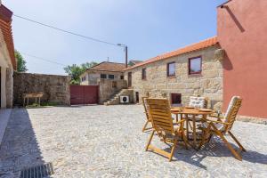 a patio with a table and chairs in front of a building at Casas do Bacelar by Liiiving in Quinchães