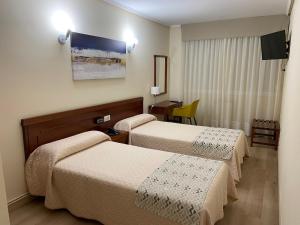 ein Hotelzimmer mit zwei Betten und einem Tisch in der Unterkunft Hotel Almendra in Ferrol