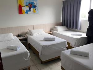 a room with three beds and a person standing in it at Hotel Itajaí Tur - Itajaí Navegantes in Itajaí +46 photos
