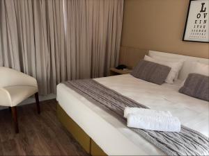 a hotel room with a bed and a chair at Hotel Itajaí Tur - Itajaí Navegantes in Itajaí