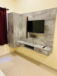 a flat screen tv on a stone wall at Sunlux Villa in Pondicherry