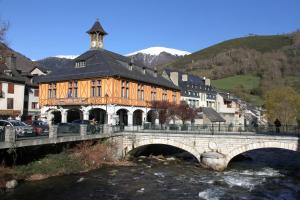 a bridge over a river with a building with a clock tower at Appartement Duplex 4 à 6 personnes in Arreau
