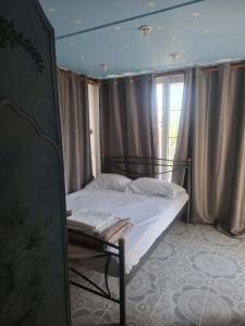 a bed in a room with a window with curtains at Διαμερισμα επάνω στο κυμα in Kineta
