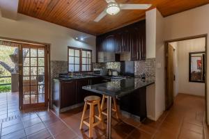 a kitchen with black cabinets and a bar with stools at Ndumu Safari Resorts in Ingwavuma