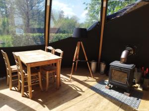 a dining room with a table and a wood stove at Bulle forestière - Etat Nature in Magnières