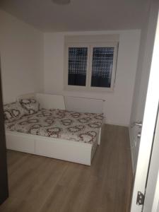 a small bedroom with a bed and two windows at Zmaj LUX 2 in Mladenovac