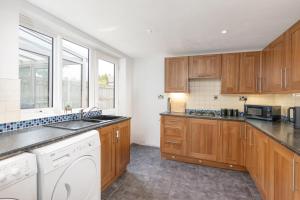 a kitchen with wooden cabinets and a white dishwasher at Billingham Rooms in Stockton-on-Tees
