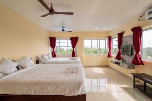 two beds in a bedroom with red curtains at Sunlux Villa in Pondicherry