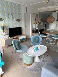 a living room with chairs and a table and a tv at Ma Mère Beach Condo Oostende in Ostend