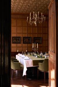 a dining room with a long table with chairs and a chandelier at Dumbleton Hall in Broadway