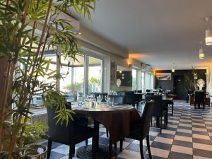 a dining room with tables and chairs and plants at Hotel De La Mer in La Tranche-sur-Mer
