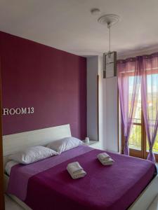 a purple bedroom with a bed with two towels on it at La Piazzetta in Torella deʼ Lombardi