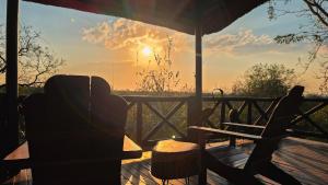 a porch with a chair and a table and the sunset at Mahlolwa in Marloth Park