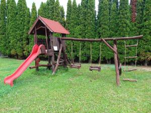 a playground with a red slide and swings at Pensiunea Praid - Parajd Panzió in Praid