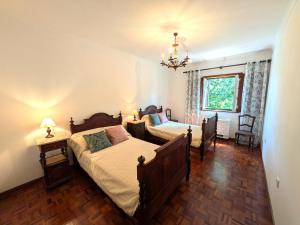 a bedroom with two beds and a chandelier at Casa da Sofia in Ponte da Barca