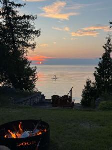 a fire pit and a person on a paddle board in the water at Egg Harbor Waterfront home in Egg Harbor