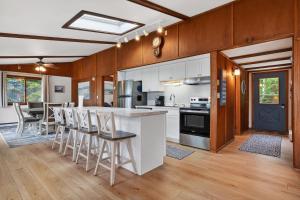 a kitchen with white cabinets and a bar with stools at Egg Harbor Waterfront home in Egg Harbor +47 photos