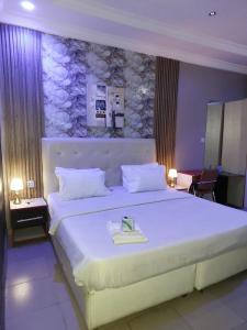 a bedroom with a large white bed with a stone wall at Pulville Boulevard Hotel in Suru Lere