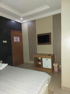 a hotel room with a bed and a television at Pulville Boulevard Hotel in Suru Lere