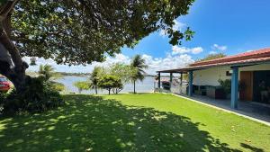 a house with a green lawn next to a body of water at Xodó da Lagoa in Beberibe