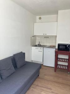 a living room with a couch and a kitchen at Studio à Bussy St Georges in Bussy-Saint-Georges