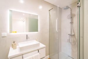 a white bathroom with a sink and a shower at Casa Amarela do Redondo in Seixal +16 photos