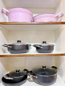 three pots and pans on shelves in a kitchen at Caramel Home in Mombasa