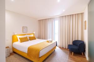 a bedroom with a large bed and a blue chair at Casa Amarela do Redondo in Seixal