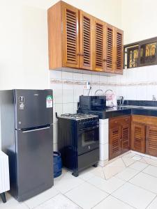 a kitchen with a black refrigerator and wooden cabinets at Caramel Home in Mombasa