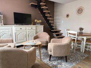 a living room with chairs and a tv and a staircase at Au Souffle Marin Maison 2 chambres in Berck-sur-Mer