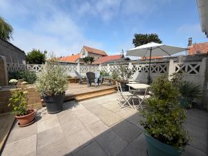 a patio with a table and chairs and an umbrella at Au Souffle Marin Maison 2 chambres in Berck-sur-Mer